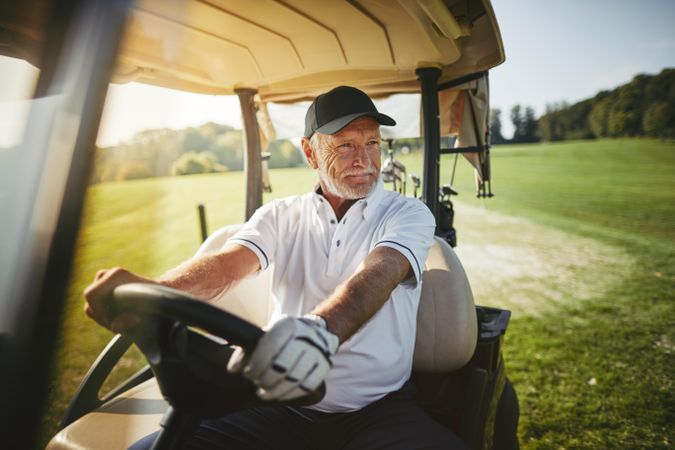 Man looking out over golf course while driving cart