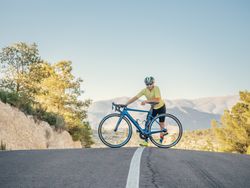 man resting while riding a bicycle on a mountain road