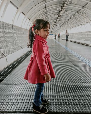 Girl in red coat standing in tunnel