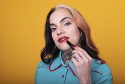 woman applying a bright red color lipstick on her lips