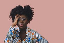 Portrait of Black woman with a pensive expression and a hand to her head