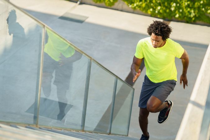 Fit man in neon T-shirt running up stairs