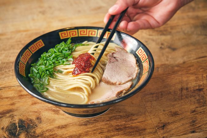 Crop person with chopsticks and delicious ramen in bowl