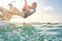 Cheerful boy hanging on rope over sea during trip in sea on cata