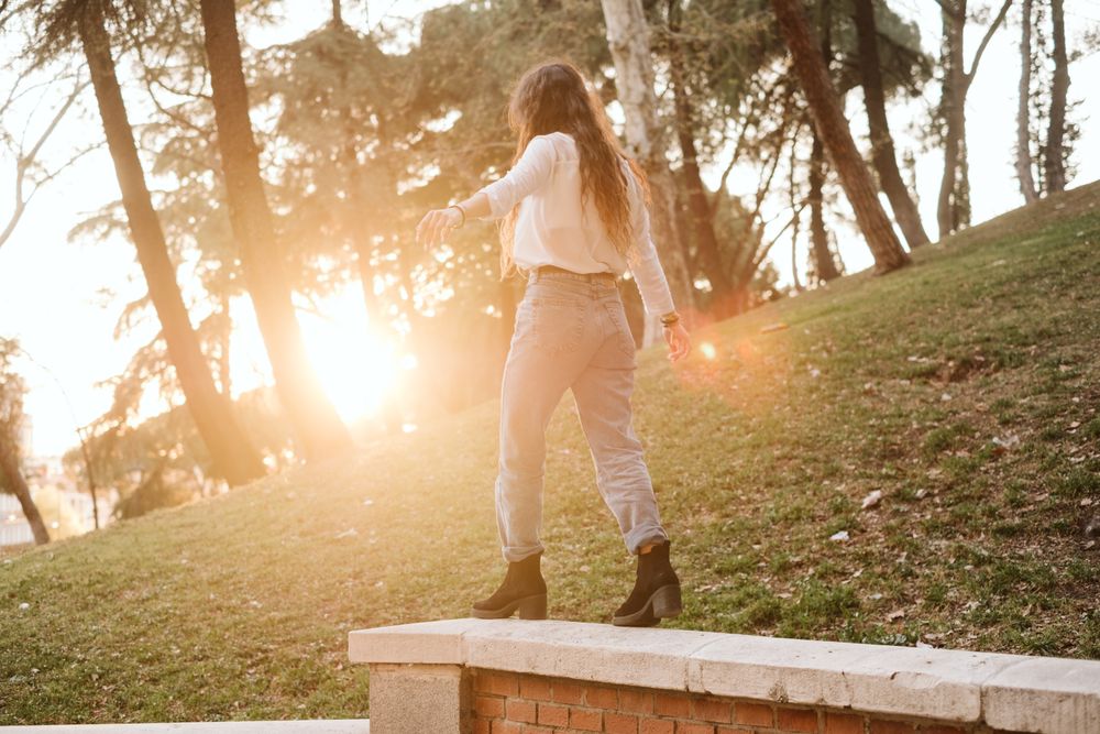 Anonymous young woman walking on border in park