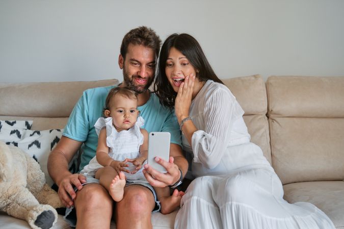 Parents with daughter watching smartphone at home