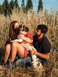 Happy couple with friendly cute dog resting outdoors