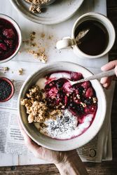 Delicious breakfast bowl with quinoa, rice and groats near tea cup and newspaper