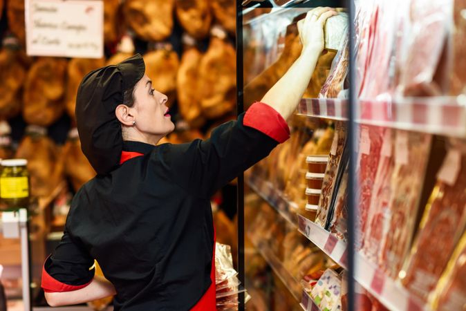 Woman in butcher shop organizing meat behind the counter