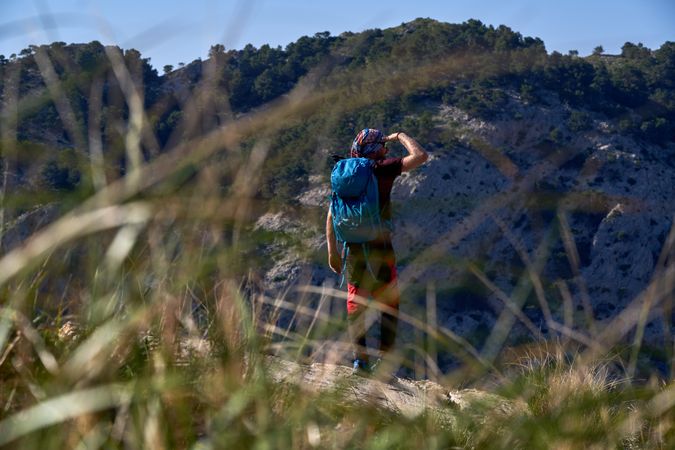 Backpacker shielding eyes on mountain