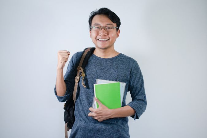 Asian student holding books and making strong gesture