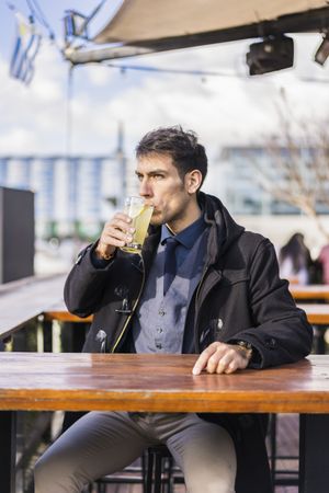 Man drinking a lemonade while sitting in a bar at the harbor