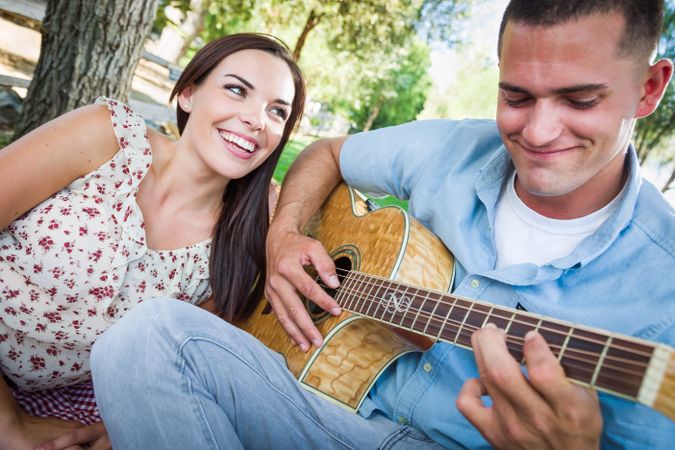 Adult Male Playing Guitar for His Girlfriend in the Park.