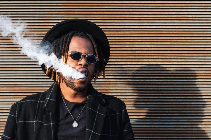 Trendy Black man in hat smoking
