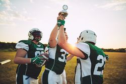 Men playing football holding up trophy