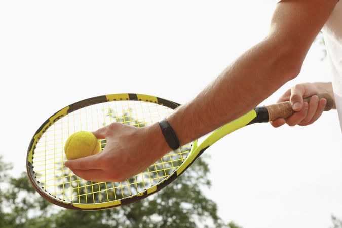 Man hold racket and tennis ball against sky