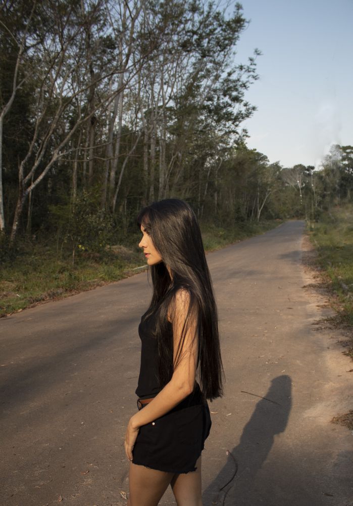 Side view of woman in dark shirt and short standing on road