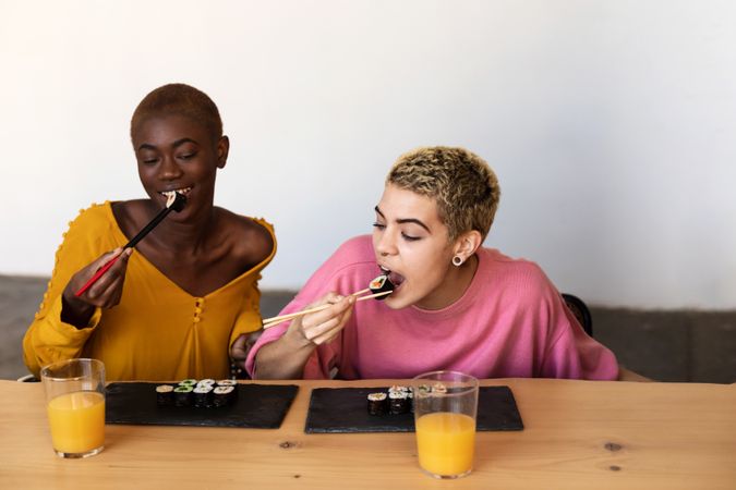 Two women enjoying sushi together at home
