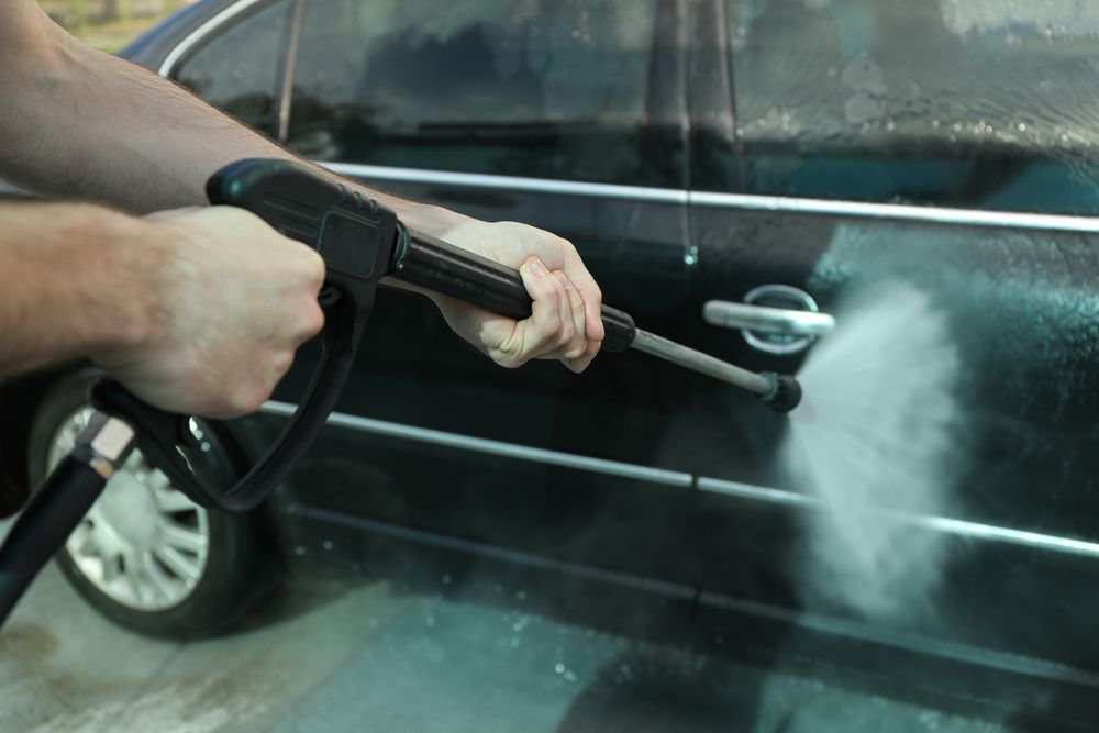 A man washes a car in a manual car wash. Clear car