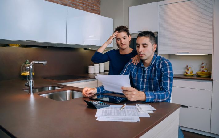 Tense couple organizing bills together in their kitchen