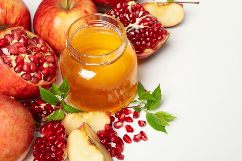 Top view of glass honey pot with pomegranate, and an apple quarters
