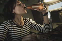 Woman with bottle near electric cooker in camper van