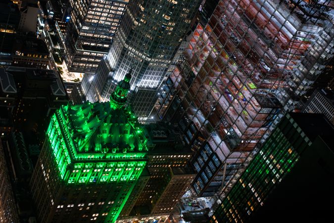 Aerial View of Lower Manhattan Architecture. Night Photo of Financial Business District from a Helicopter. Scenery of Historic Office Tower, Illuminated with Green Light on a Roof