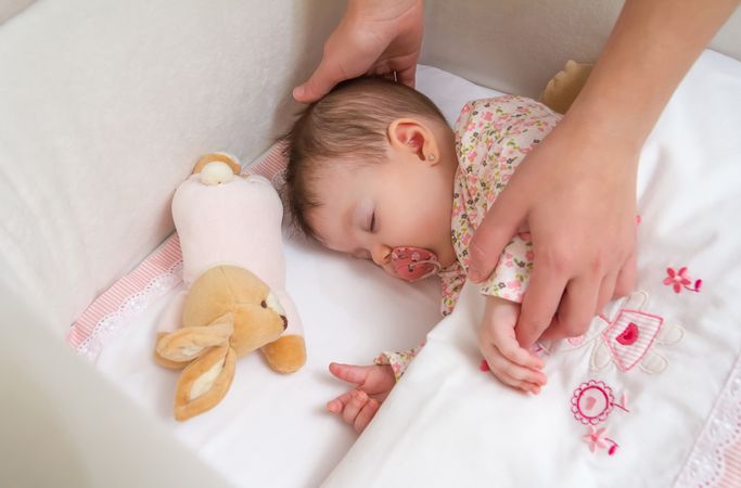 Hands of mother with her baby girl sleeping