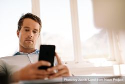 Young male professional using smart phone while working remotely bEzVN0