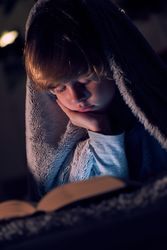 Boy reading book in darkness