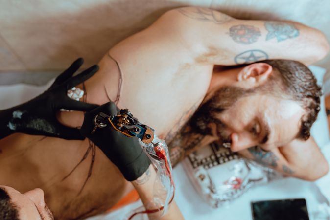 Man receiving chest tattoo