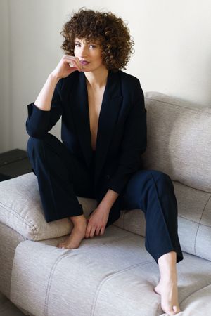 Woman in navy suit lounging on sofa