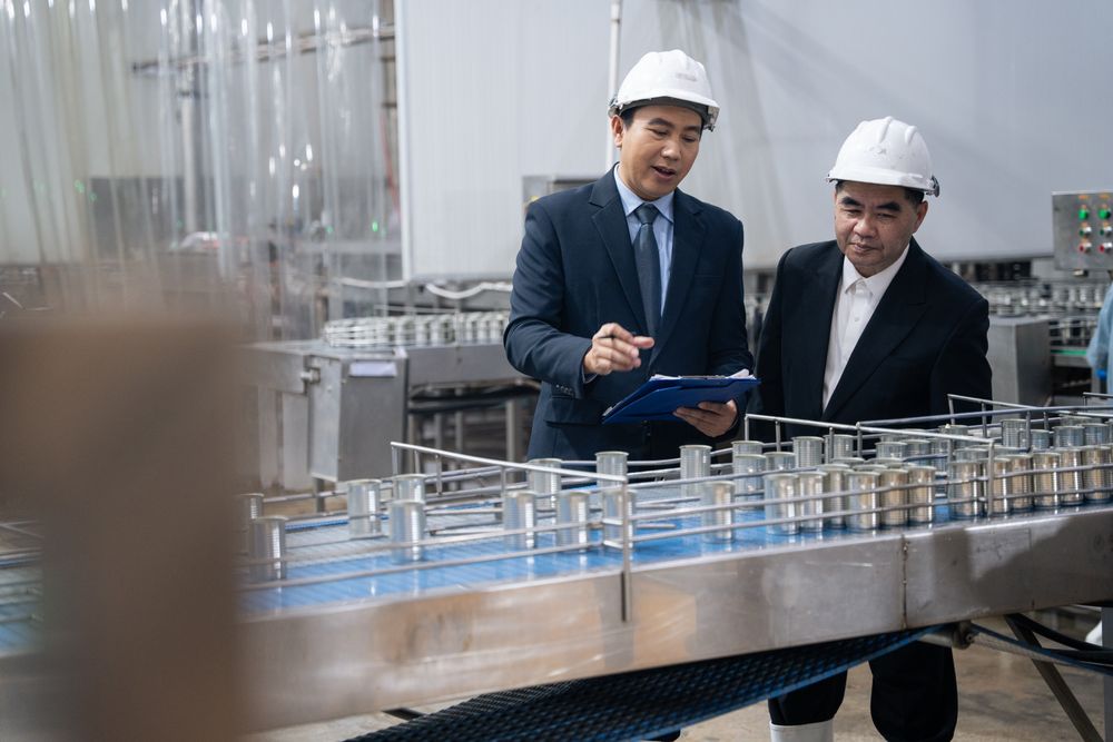 A businessman inspecting canned fish on conveyor belt at the factory