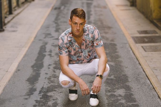 Handsome man sitting on asphalt