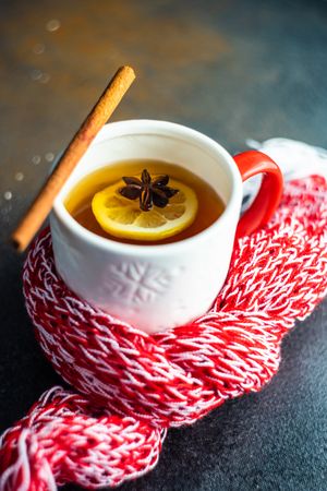 Mug of hot wintry drink wrapped in red woolen scarf