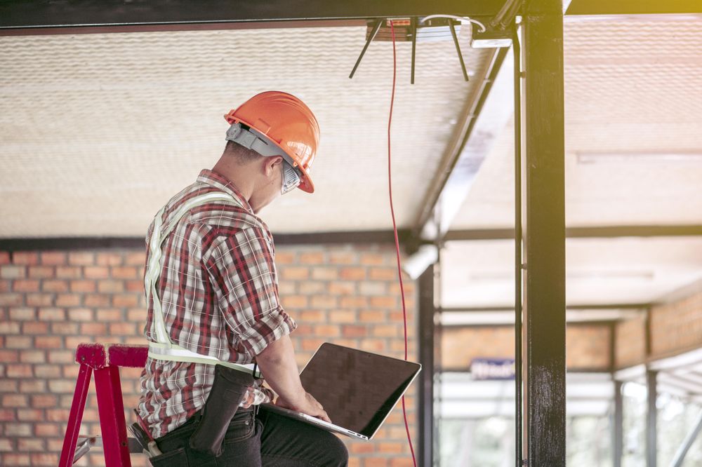Back view of an engineer in bump cap using computer