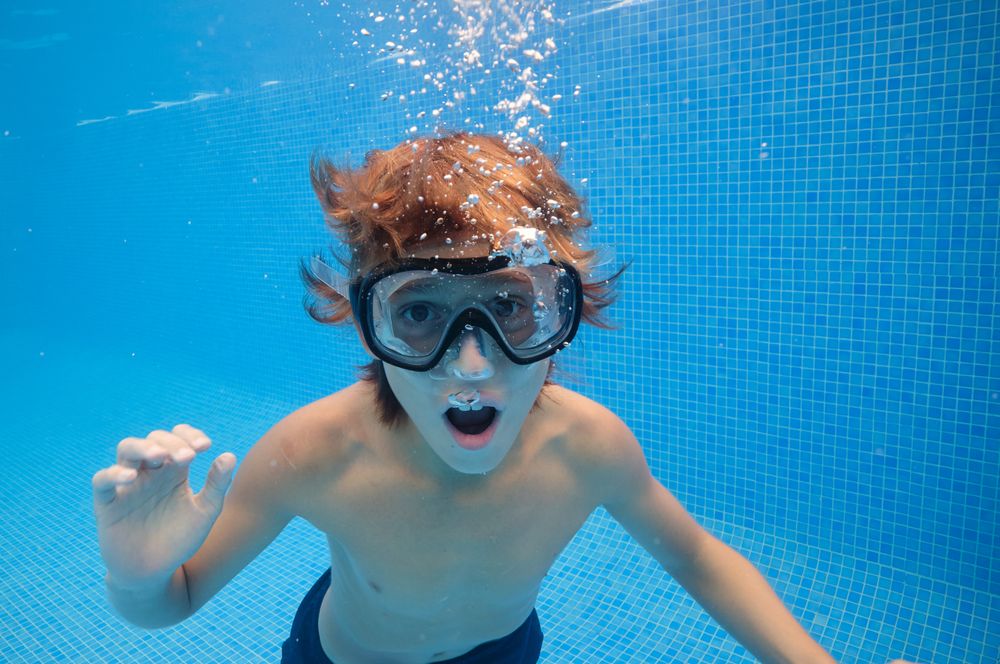 Boy with mouth opened swimming in pool