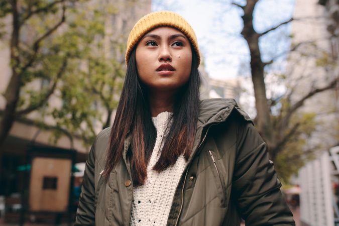 Young woman in yellow knit cap looking to side outdoors