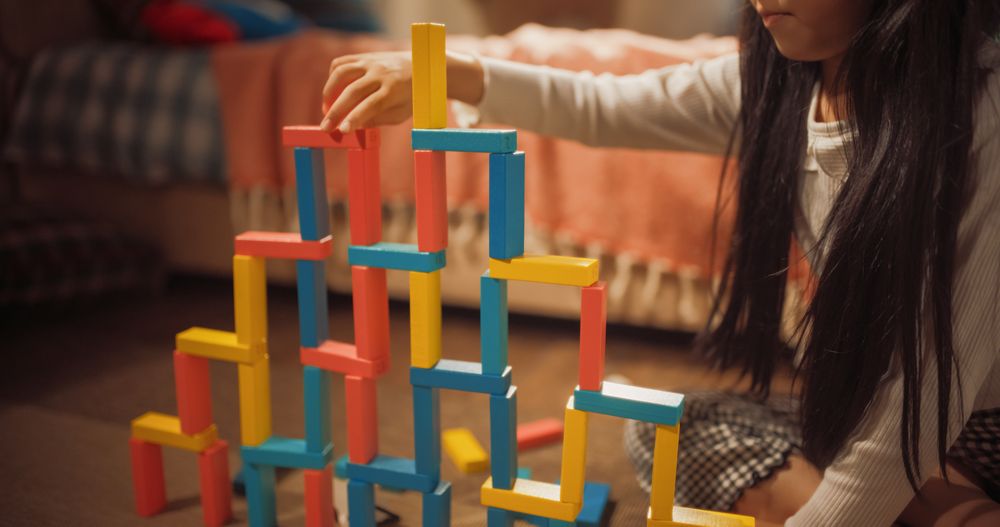Portrait of Focused Little Girl Playing with Construction Building Blocks while in Children's Room.