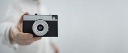 Man holding retro camera on light background