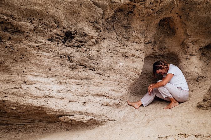 Barefoot woman meditating in rock cavity