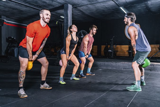 Athletic friends exercising with weight in gym