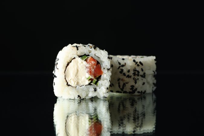 Delicious sushi rolls on dark mirror background. Japanese food
