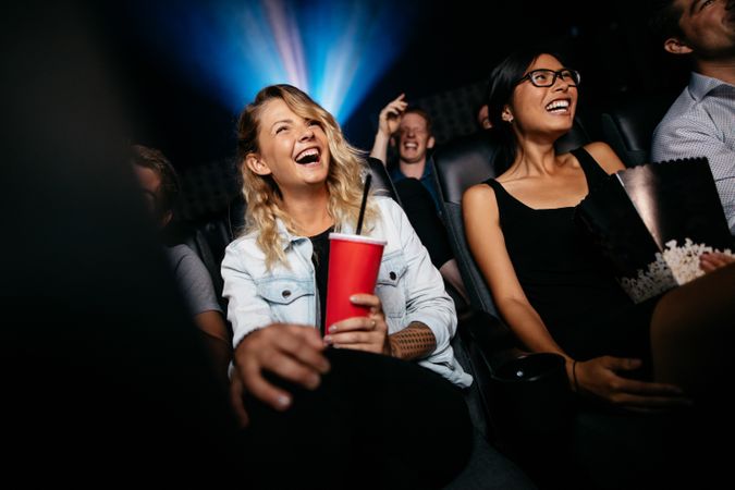 Young people laughing while watching film in movie theater