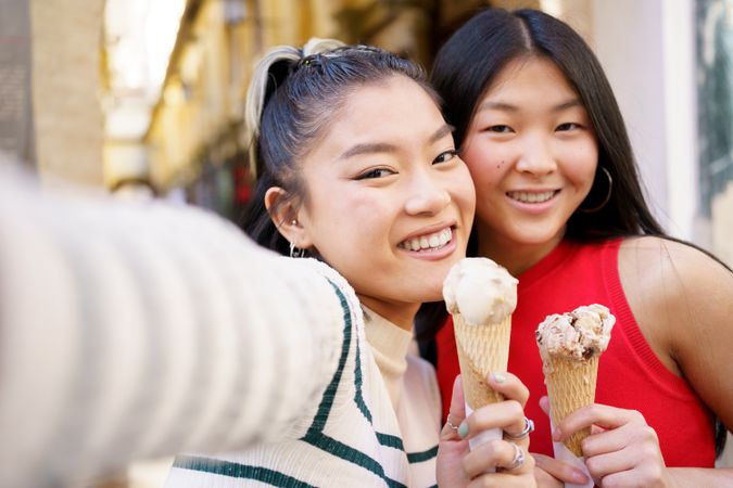 Two women taking selfie with ice cream cones outside