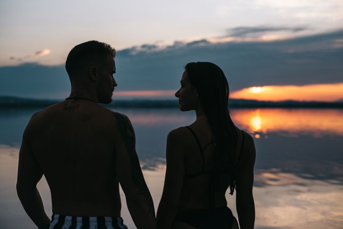 Couple hugging on beach of lake at sunset