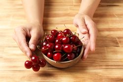 Ripe cherry fruits in a bowl on a wooden background