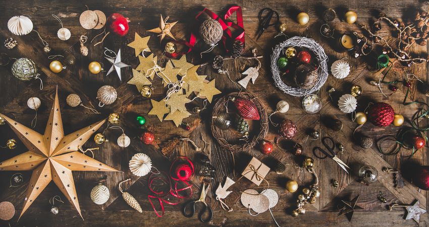 Holiday decorations of stars, baubles, scissors and ribbon strewn on wooden table