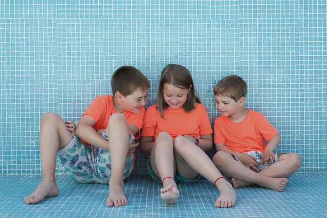 Children sitting in empty pool and reading book