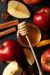 Apples, cinnamon and honey with dipper on dark background with copy space